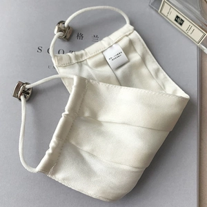 Detail of silk face mask featuring adjustable elastic ear loops and silver metal buckles