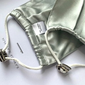 Detail of mint green mulberry silk mask with adjustable ear loops and quality label