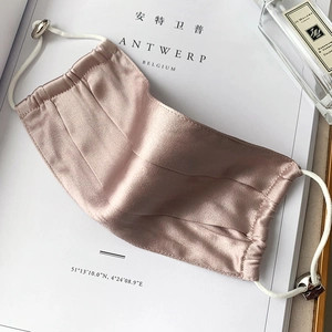 Breathable silk face mask in lotus pink with adjustable ear loops on a magazine background