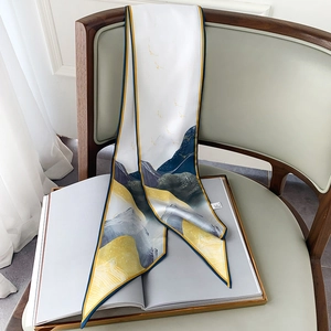 Dettaglio di un foulard di seta bianco con stampa paesaggistica su sedia in legno