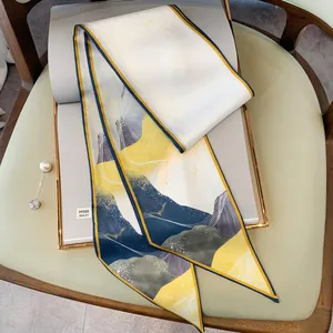 Dettaglio di un foulard sottile in seta con stampa astratta e spilla di perle sul libro