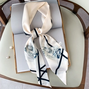 Dettaglio di un foulard in seta con stampe di cani e una spilla di perle