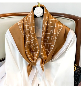 Détail d'un foulard en soie caramel à motif géométrique sur un chemisier blanc élégant