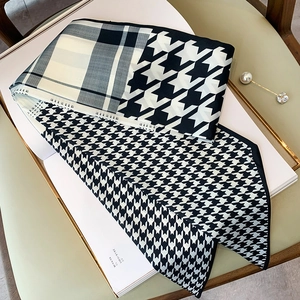 Dettaglio di una sciarpa stretta in seta con motivi pied de poule e patchwork nero bianco