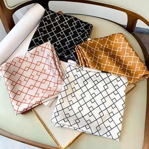 Détail de foulards en soie aux motifs géométriques présentés sur un plateau doré