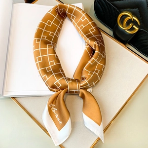 Foulard en soie jaune ocre avec motifs géométriques blancs sur un plateau de luxe