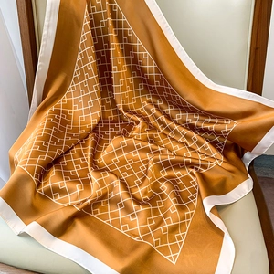 Gros plan d'un foulard en soie jaune moutarde avec motifs géométriques sur une chaise