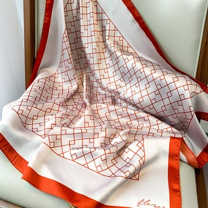 Détail d'un foulard en soie à grille orange et inscription 'flower' sur fond beige doux