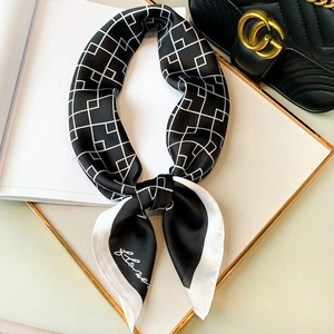 Élégant foulard en soie noir et blanc à motifs géométriques noué sur un support