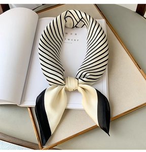 Detailed view of striped silk satin square scarf with elegant knot on a tray