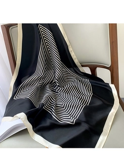 Close-up of silk-like square scarf with black and white chevron stripes on a leather chair