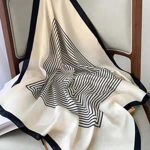 Elegant black and white striped silk square scarf displayed on a vintage chair