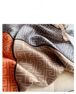 Detailed fabric display of faux silk scarf with geometric orange and gold patterns