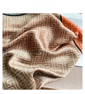 Close-up of silk scarf with brown geometric maze pattern and orange border detail