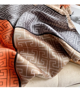 Detail of silk scarf showing orange and grey geometric patterns and glossy fabric texture