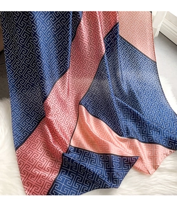 Detailed close-up of geometric greek key patterns on silk scarf with pink and blue colors