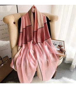 Detail of elegant silk scarf with geometric patterns draped on a pink armchair