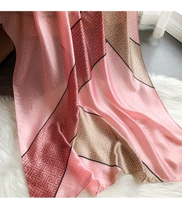 Detail of pink and brown silk scarf with geometric pattern on soft plush carpet