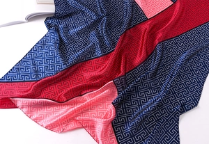 Detailed view of color-blocked silk scarf with classic Greek key geometric patterns