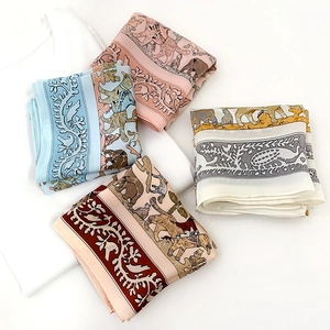 Detail of silk scarves showing bird and animal prints in pink, blue, beige and brown tones