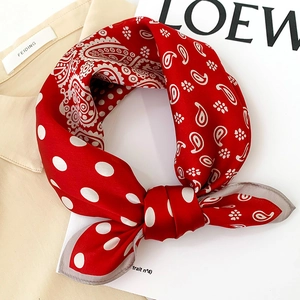 Gros plan d'un foulard en soie rouge avec motifs paisley et pois blancs sur chemise
