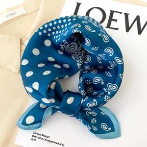 Foulard en soie bleu foncé à motif paisley et pois sur une chemise beige et magazine