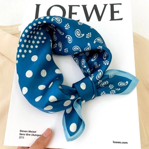 Détail d'un carré en soie bleu marine avec motifs paisley et pois blancs élégants