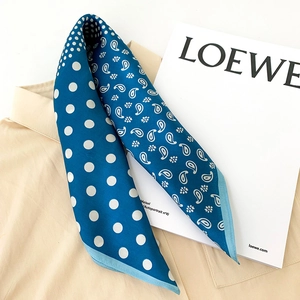 Détail d'un foulard en soie avec motifs paisley et pois blancs sur une chemise beige