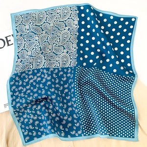 Détail d'un foulard carré en soie avec motifs cachemire bleus et pois en pliage doux