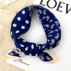 Foulard en soie bleu marine avec motifs paisley et pois, noué de manière élégante et chic