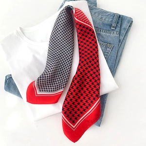 Détail d'un foulard en soie à motif pied-de-poule rouge et noir sur un t-shirt blanc