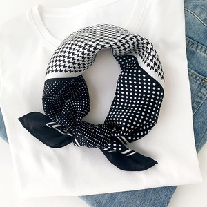 Détail du foulard en soie montrant le motif pied-de-poule et pois avec un nœud élégant