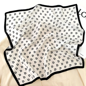 Detail of silk square scarf with vintage D-letter pattern and elegant black borders