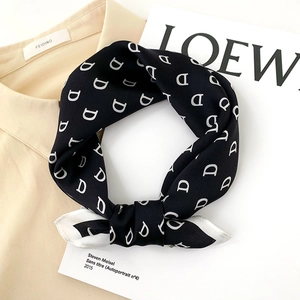 Elegant silk scarf with black and white D-letter pattern tied in a stylish knot