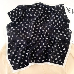Close-up of silk square scarf with luxury black and white monogram pattern texture