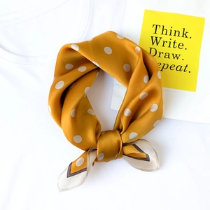 Mustard yellow silk scarf with white polka dots on a white t-shirt background
