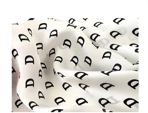 Detailed view of silk scarf fabric with repeating black D-letter monogram print