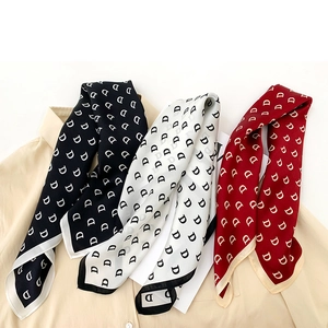 Detail of silk scarves in black, white, and burgundy with stylish letter D prints