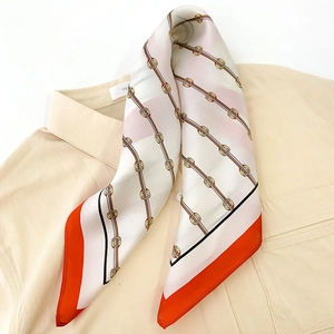 Classic silk scarf with equestrian chain patterns and orange border on a beige shirt