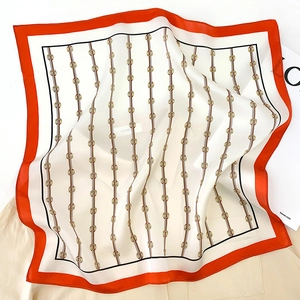 Close-up of silk square scarf with chain patterns and bright orange border details