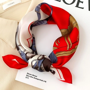 Detail of red silk scarf with equestrian stirrup patterns on a beige shirt