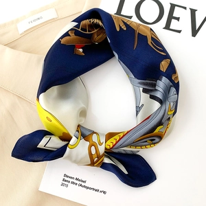 Detail of silk scarf with equestrian horse prints styled on a beige shirt collar