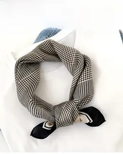 Détail d'un foulard en soie à motif pied-de-poule noir et blanc noué sur un t-shirt blanc