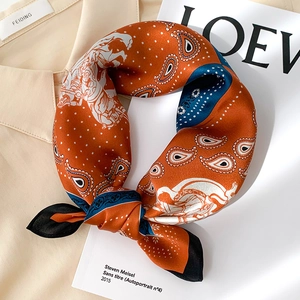 Détail d'un foulard en soie orange avec motifs paisley et calèche sur une chemise