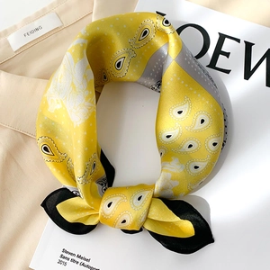 Vue détaillée d'un foulard en soie jaune à motif cachemire sur fond de magazine chic