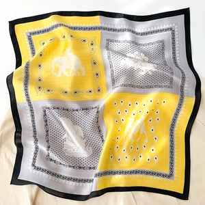 Détail d'un foulard en soie avec imprimés éléphant et voilier et bordure jaune