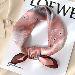 Gros plan sur la texture du foulard en soie à motif paisley rose sur un magazine
