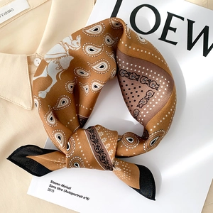 Détail d'un foulard en soie aux motifs paisley et chevaux sur chemise et magazine