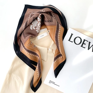 Détail d'un foulard en soie à motifs pied-de-poule et paisley sur une chemise beige