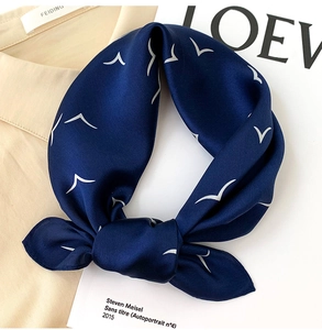 Detail of navy silk scarf with white seagull prints tied as an elegant bow on a shirt